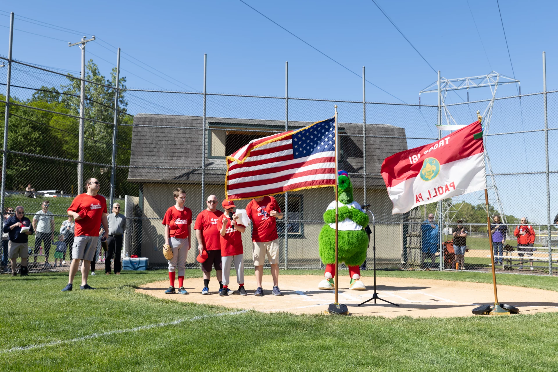 6V0A5590 Children and adults on a baseball field with the Phillie Phanatic. One player is speaking into a microphone.
