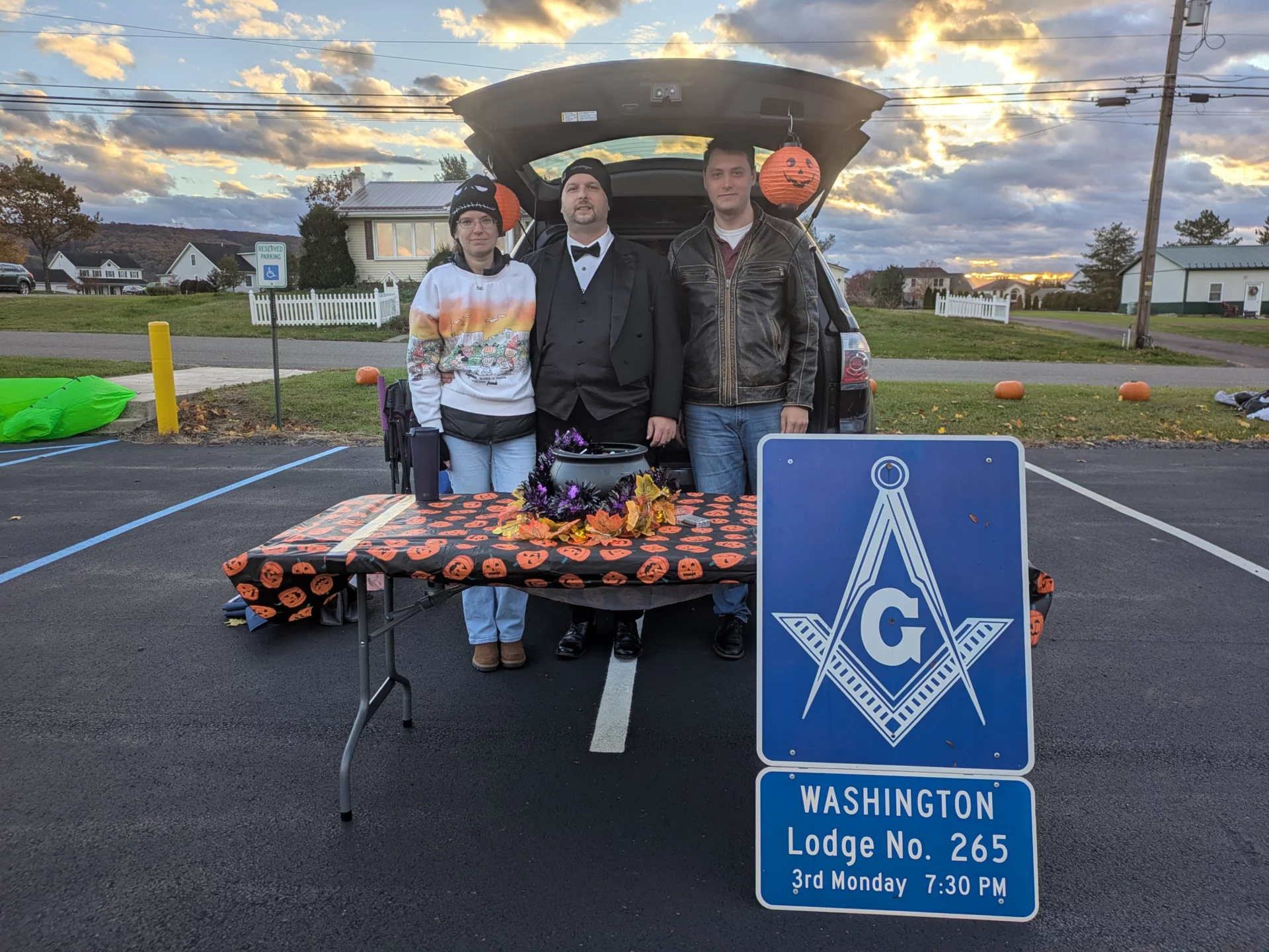 Small group of people standing behind a Halloween themed table with a decorated car behind them.