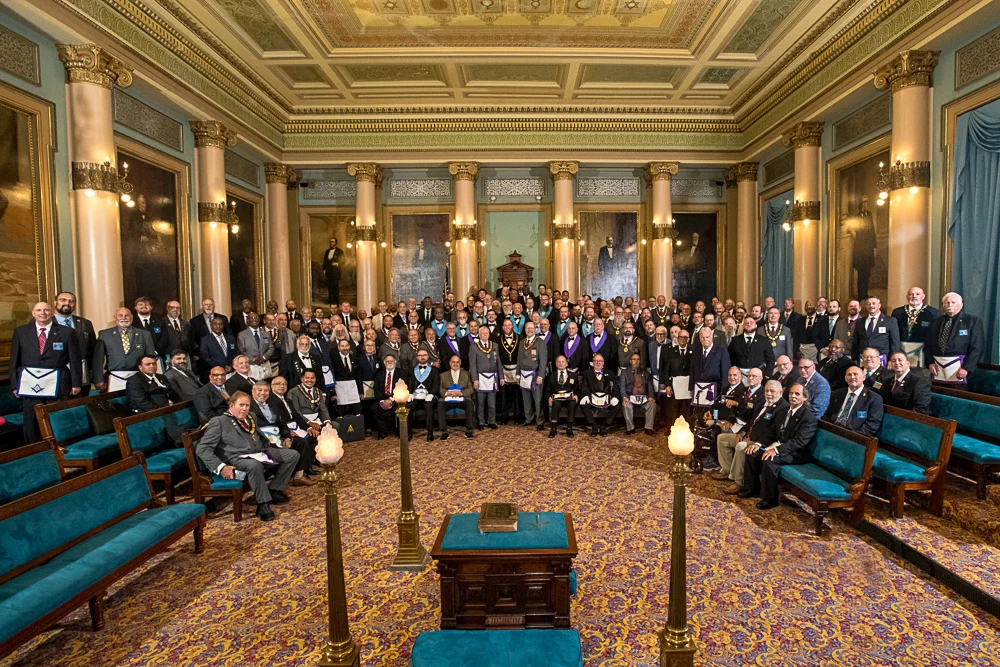 GLPANJ08.22-0142b Large group of Masons standing and seated together in a lodge room.