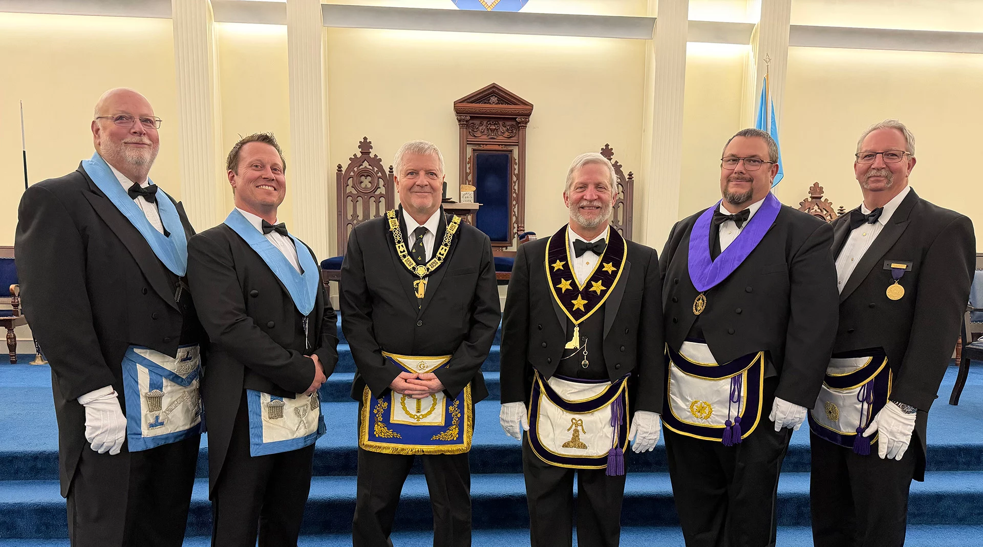 Smiling group of Masons standing in a lodge together.
